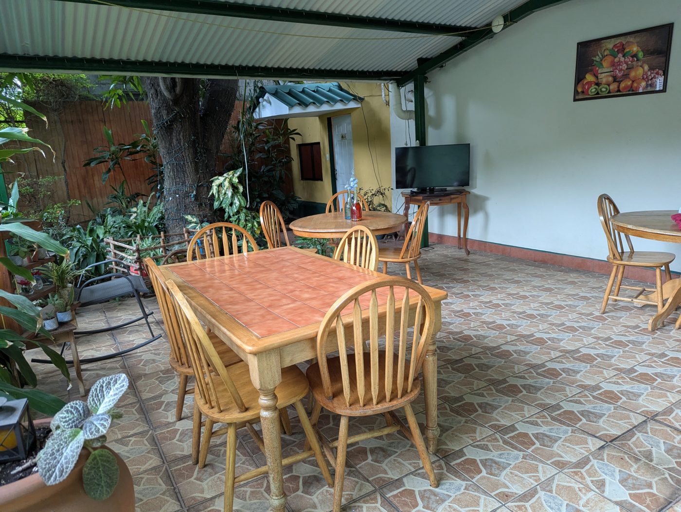 Comedor techado del Hostal Della Nonna, con mesas de madera y el jardín al fondo