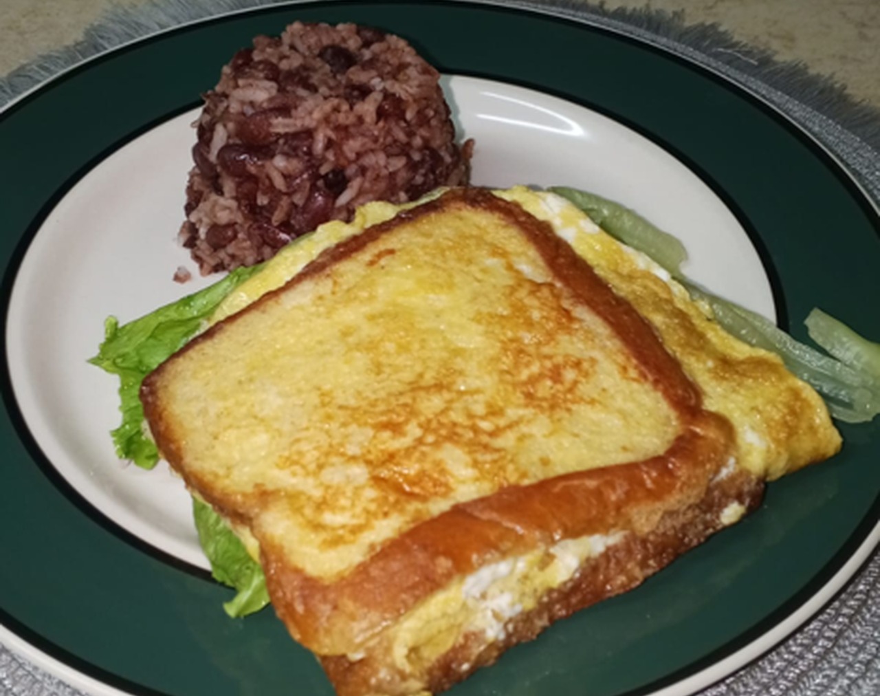 Desayuno en Hostal Della Nonna, emparedado de huevo con pan tostado, jamón y queso derretido, acompañado de gallo pinto casero y lechuga fresca