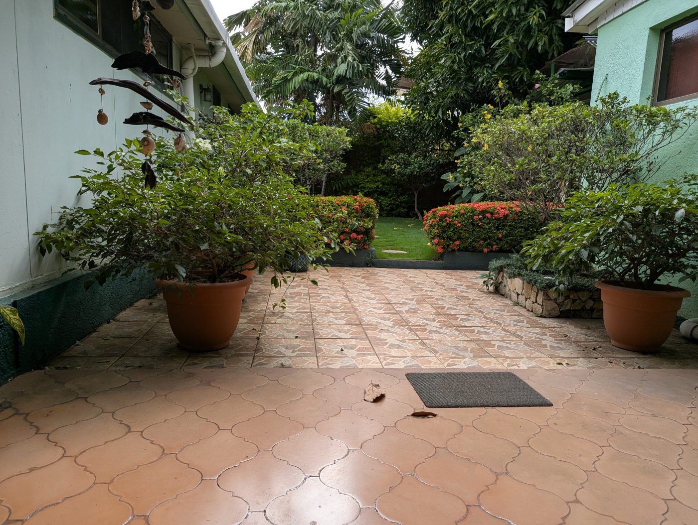 Patio del Hostal Della Nonna, con macetas grandes y césped al fondo