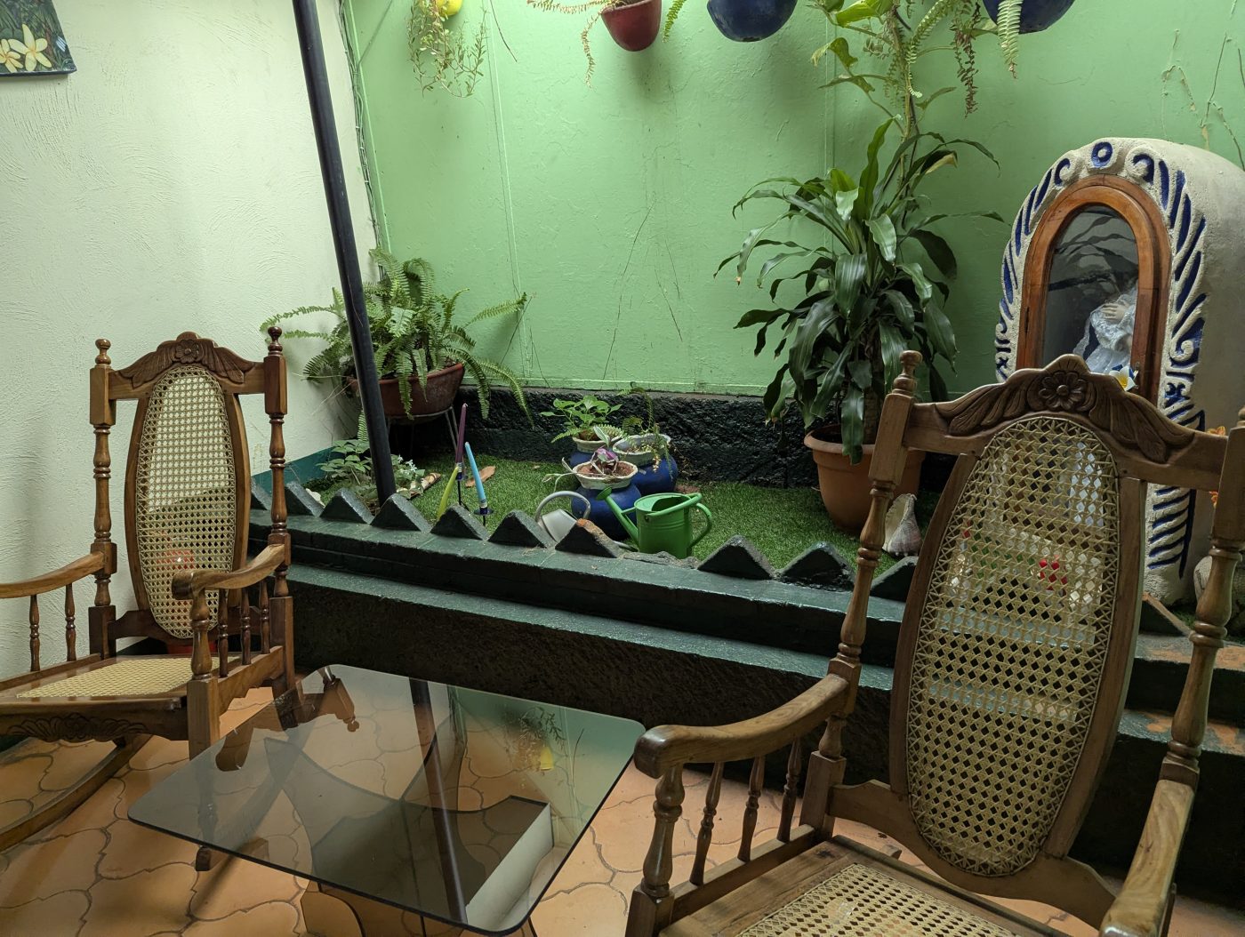 Rincón de mecedoras de mimbre del Hostal Della Nonna, rodeado de plantas